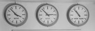Trois horloges sur un mur indiquent des fuseaux horaires différents : Berne, Greenwich Mean Time et New York. - vue agrandie