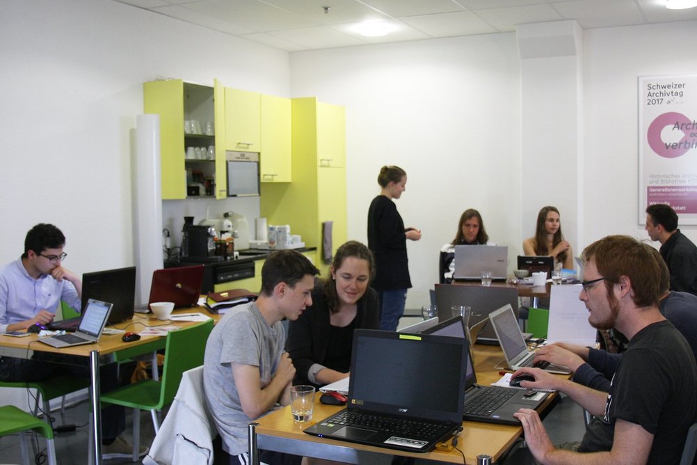Studenten arbeiten gemeinsam in der Caféteria des PTT-Archivs an ihren Wikipedia-Beiträgen.