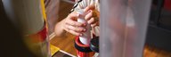 Close-up of a student's hands putting a letter into the pneumatic tube. - enlarged view