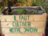 Ein Hochbeet-Kasten aus Holz mit Erde drin. Der Kasten hat eine grüne Aufschrift auf Französisch. Dort steht: Il faut cultiver notre jardin.