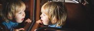 Ein Kind schaut fasziniert aus dem Fenster eines Postautos. - vergrösserte Ansicht