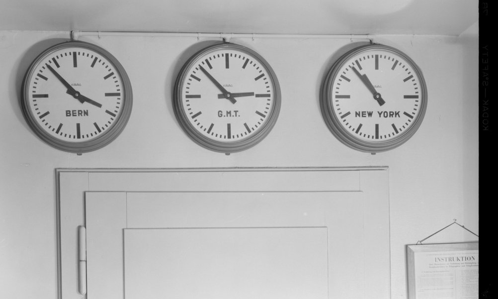 Three clocks on a wall show different time zones: Bern, Greenwich Mean Time and New York.