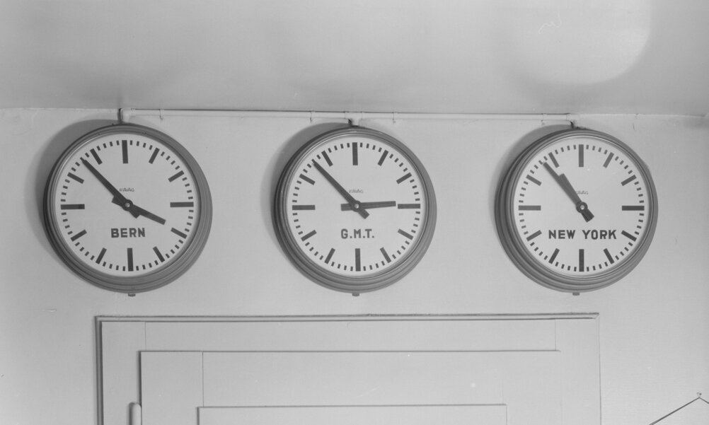 Three clocks on a wall show different time zones: Bern, Greenwich Mean Time and New York.