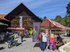 In front of a wooden house, the Chüechlihus in Langnau, there are market stands where people are talking.