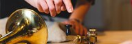 Ein Posthorn und ein Morsegerät stehen auf einem Tisch, eine Hand ist gerade im Begriff, auf den Morsetaster zu drücken. - vergrösserte Ansicht