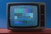 Im Bild ist ein Fernsehgerät der 1970er-Jahre zu sehen. Darauf das farbige Testbild von SRG und PTT. - vergrösserte Ansicht