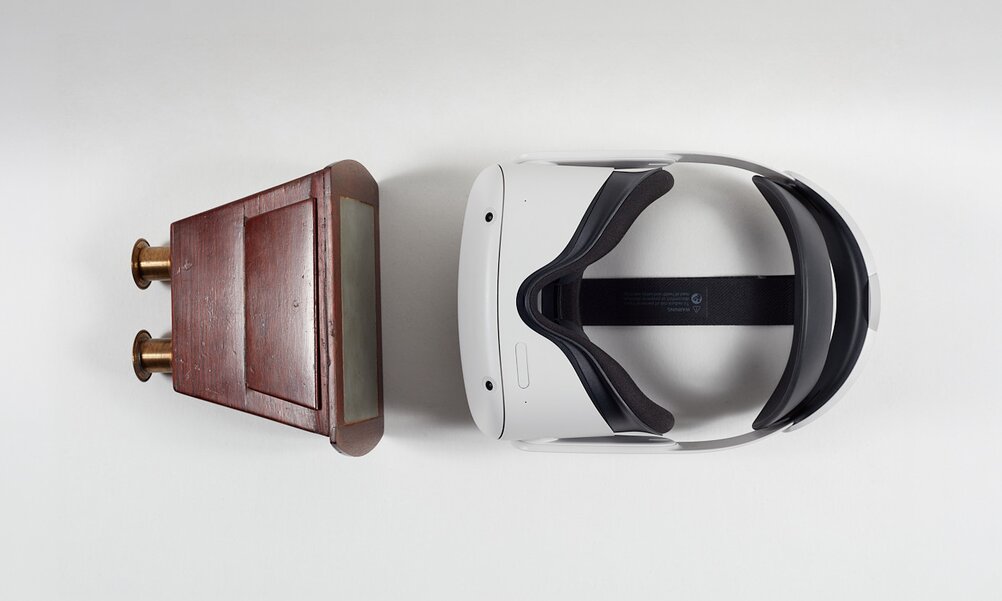 Eine Virtual-Reality-Brille liegt auf weissem Grund - ihr gegenüber ein historisches Stereoskop aus Holz.