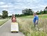 Eine Gebotsschieberin auf einer Landstrasse, kritisch beobachtet von einem Mann, der im Feld steht.