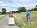 Eine Gebotsschieberin auf einer Landstrasse, kritisch beobachtet von einem Mann, der im Feld steht.