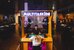 Eine interaktive Station leuchtet im Halbdunkel des Museums für Kommunikation: Zwei Personen sitzen sich gegenüber an einem Spieltisch, darüber die Leuchtschrift "Multitasking". - vergrösserte Ansicht