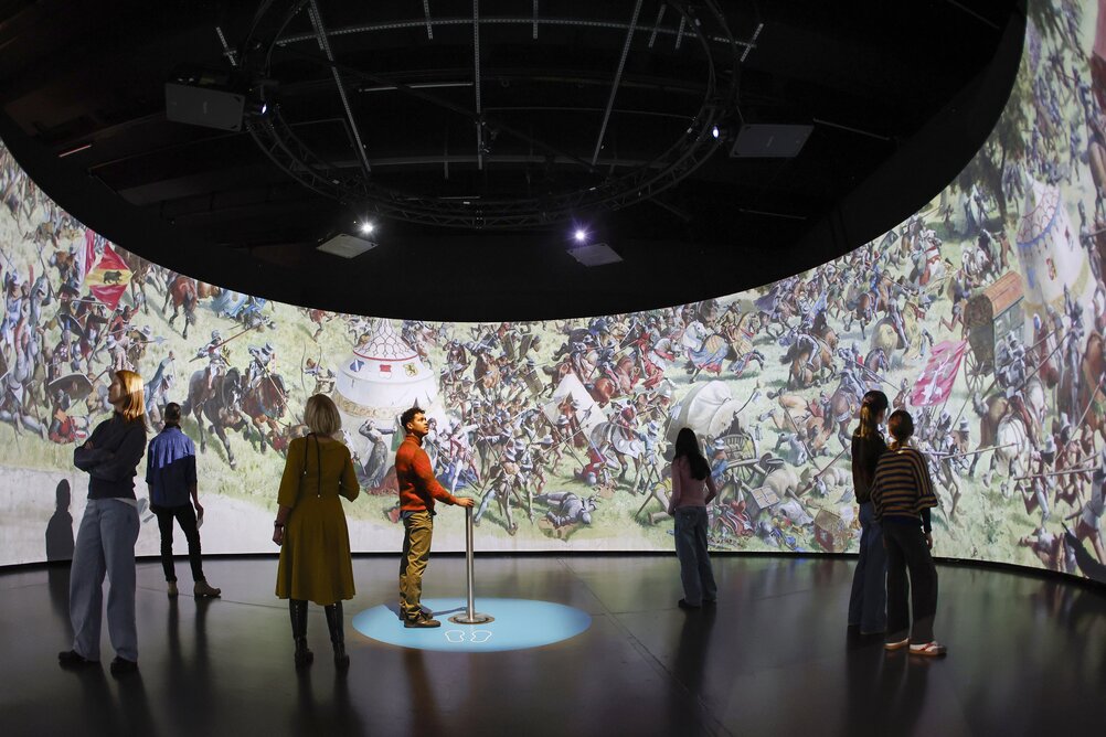 [Translate to English:] Besucher:innen betrachten die 360° Bildinstallation