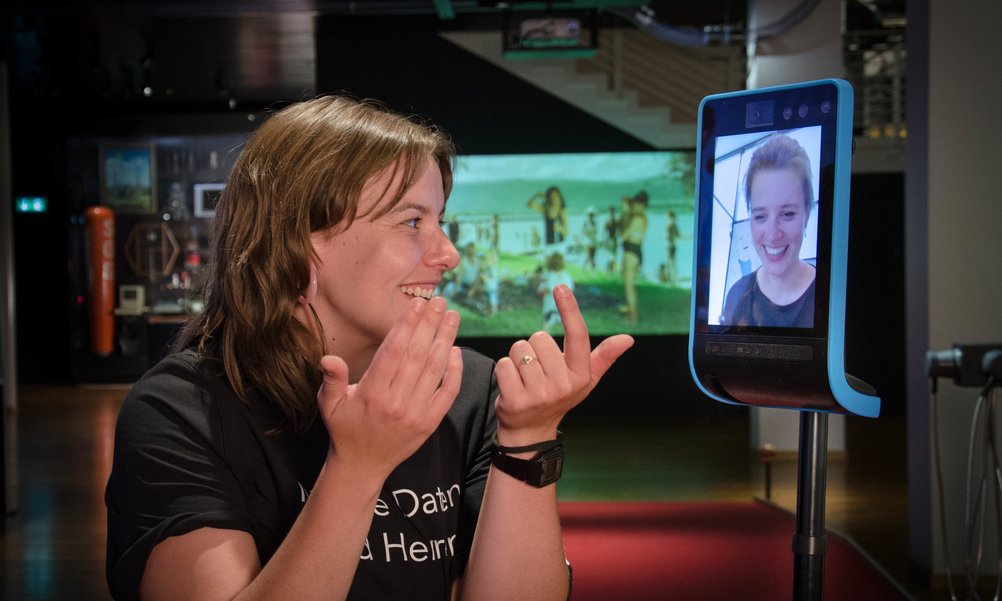 [Translate to English:] Eine Frau steht vor einem Telepräsenzroboter.