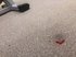 Eine rote Markierung auf einem graumelierten Teppich.