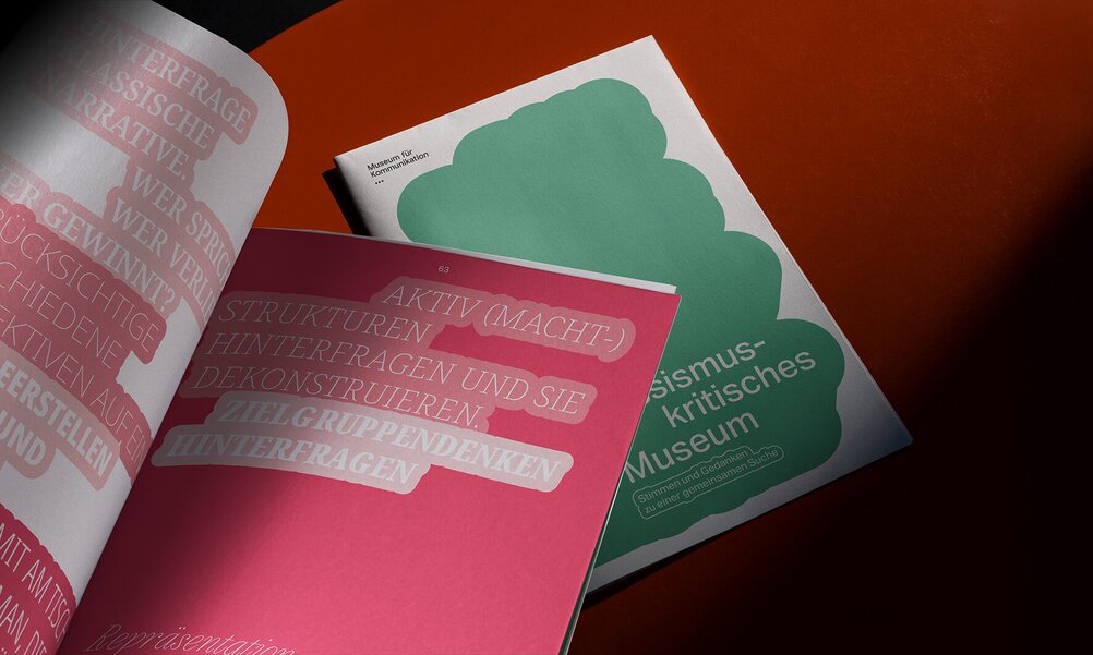 Two issues of a magazine lie on a wooden surface – one closed, one open. The title and text are visible. Everything is designed in green and red.