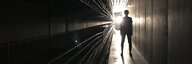 Silhouette einer Person in dunklem Gang, am Ende eine Lichtquelle. - vergrösserte Ansicht