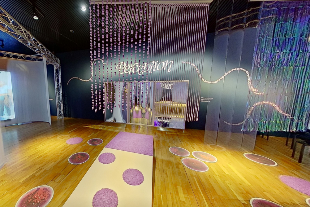 Blick in die Ausstellung DANCE mit einem Parcours, der zum Bewegen einlädt (Fadenvorhänge von der Decke, Punkte am Boden, eine kleine Rampe).