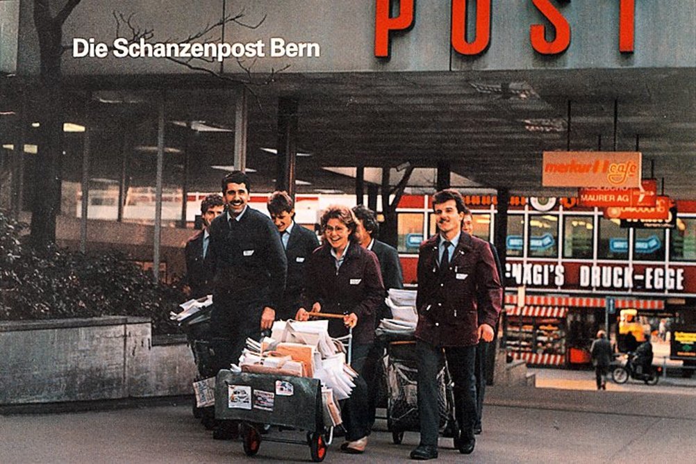 A historic picture of the Schanzenpost in Bern: proud postmen and postwomen swarm out in front of the entrance, packed full of mail.