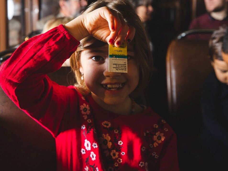 Ein lachendes Kind hält ein altes Reiseticket vor seinem Gesicht. - vue agrandie