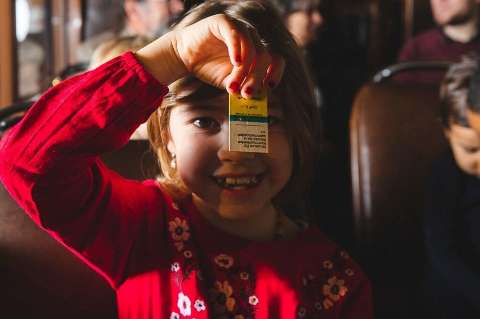 Ein lachendes Kind hält ein altes Reiseticket vor seinem Gesicht. - vergrösserte Ansicht