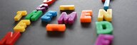 Auf einer dunklen Fläche liegen bunte Magnetbuchstaben. Mit leichter Unschärfe fotografiert erkennt man die Wörter "Themen", "Suchen" und "Finden". - vergrösserte Ansicht