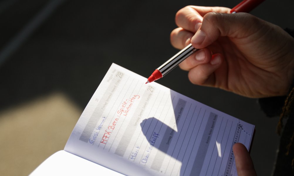 Une main note un rendez-vous dans un agenda.