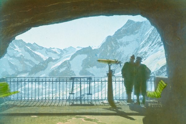 Historische Aufnahme eines Stollenfensters mit Fernrohr. Zwei Personen blicken auf das Bergpanorama.