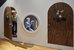 Two children are playing in a little house under the stairs. One is looking out of the half-open door. The other is visible through a round window. It is playing with wooden cubes. - enlarged view