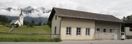 Le bâtiment discret au premier plan est le central téléphonique historique de Versam. On peut voir une église et de hautes montagnes en arrière-plan. - vue agrandie