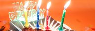Auf einem Tellerchen liegt ein Schokoriegel mit vier brennenden Kerzchen und einem Happy-Birthday-Schriftzug. - vergrösserte Ansicht
