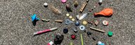 Sur le sol se trouve un fatras de petits objets disposés en forme de rayon : Des boutons, des stylos, un ballon et bien plus encore. - vue agrandie