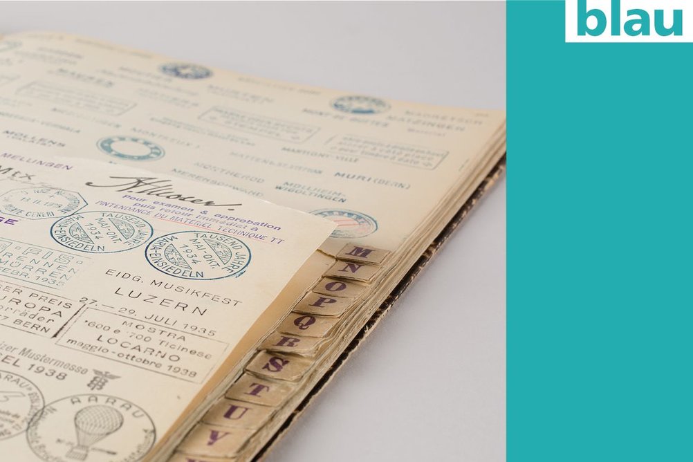 A historical booklet with letter indexes, filled with a multitude of stamps - next to it is a coloured area in blue.