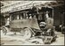 Historisches schwarz-weiss Bild. Postauto der frühsten Generation noch mit Vollgummipneus in einer grossen Halle. Am Heck des Postautos ist ein grosses Stück abgerissen.
