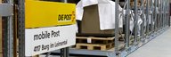 A shelf in a museum depot. Collection objects can be seen packed in pallets; a post office sign can be seen in the foreground. - enlarged view