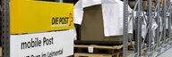 A shelf in a museum depot. Collection objects can be seen packed in pallets; a post office sign can be seen in the foreground. - enlarged view