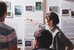 Drei Besuchende stehen vor einer Ausstellungswand und eine Person zeigt auf etwas an der Wand - vergrösserte Ansicht
