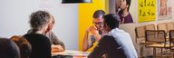 Four contented people sit at a table and play a game. - enlarged view