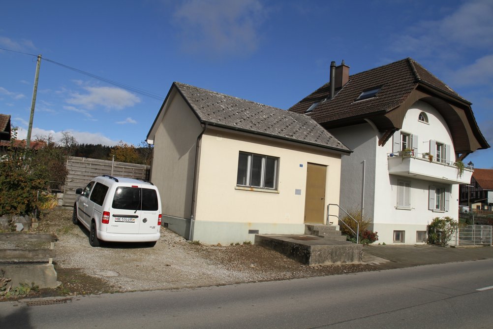 Das kleine Haus zwischen einem Auto und einem Wohnhaus ist die historische Telefonzentrale von Frieswil.