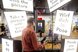 Un homme se tient dans la lumière d'une station photo. Devant lui, des affiches lumineuses avec des inscriptions telles que "Jette-toi dans la pose".