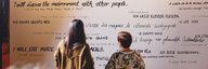 Two people stand in front of a wall that is written full of good climate intentions. - enlarged view