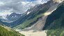 Aufnahme eines Tals in Berglandschaft. Am rechten Hang ist eine riesige Geröll und Eislawine zu sehen, die unten einen Teil des Tals aufgefüllt und das Dorf Blatten verschüttet hat.