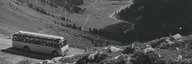 Photo historique d'un car postal sur une route de col, en arrière-plan on peut voir le fond de la vallée. - vue agrandie