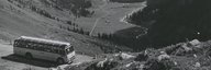 Historical picture of a post bus on a pass road, the valley floor can be seen in the background. - enlarged view