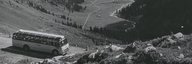 Historisches Bild eines Postautos auf einer Passstrasse, im Hintergrund ist der Talboden zu sehen. - vergrösserte Ansicht