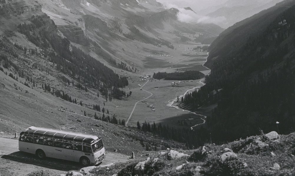 Photo historique d'un car postal sur une route de col, en arrière-plan on peut voir le fond de la vallée.