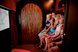 Four children sit tightly packed on a bench in a little house and look spellbound at a screen.