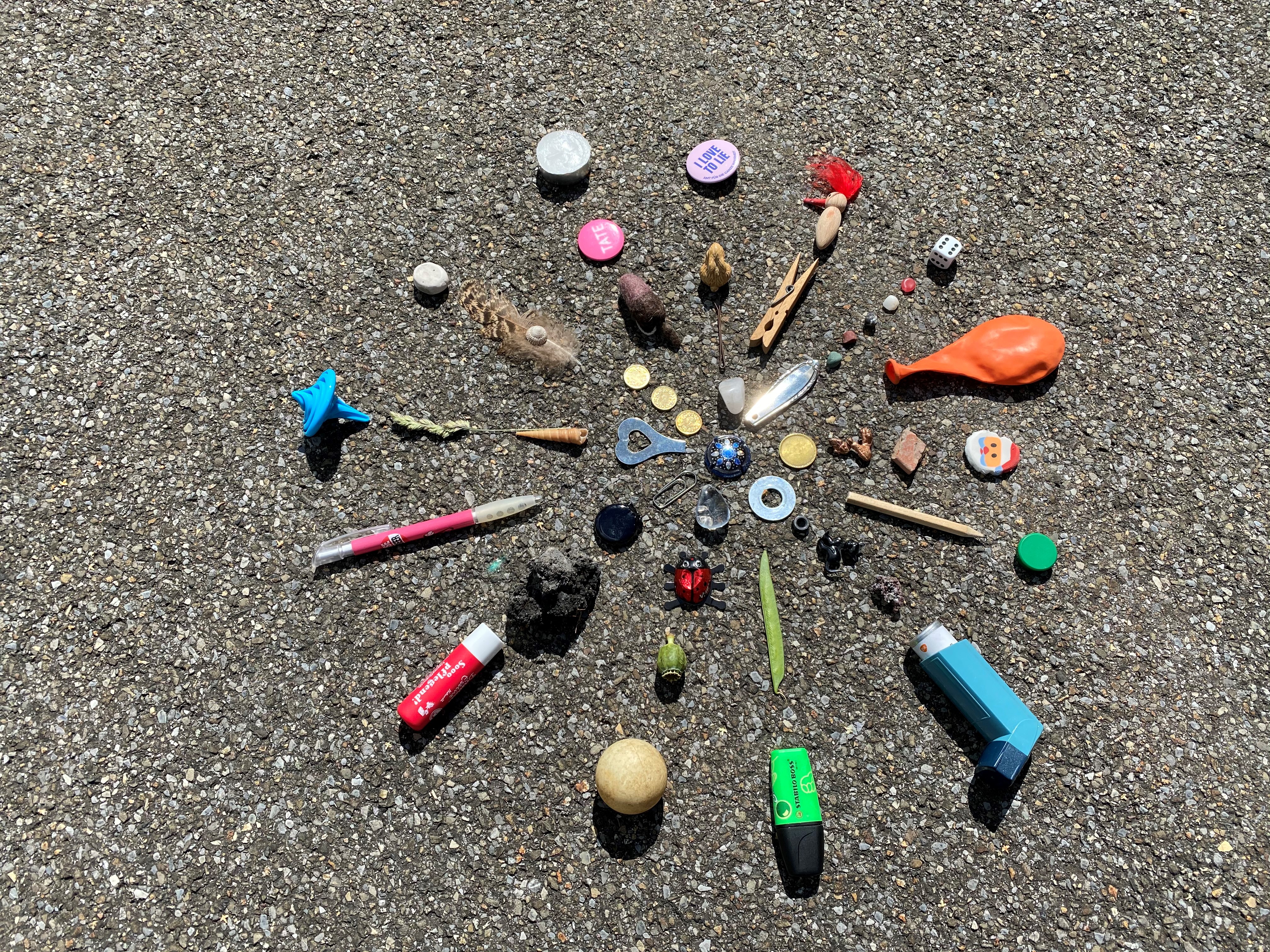 On the floor, arranged in a radiant pattern, lies a hodgepodge of small objects: Buttons, pens, a balloon and much more. - enlarged view